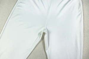 Detailed close-up of white stretch pants showing stitching and smooth fabric texture