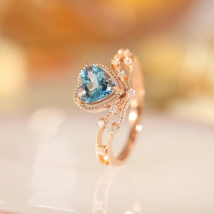 Rose gold heart-shaped ring with light blue topaz stone and small side diamonds