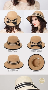 Detail view of beige straw hat featuring black ribbon bow and metallic M letter accent