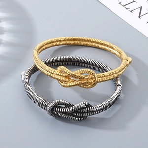 Detailed view of knot-shaped snake bone textured bracelets in gold and antique silver finish