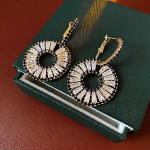 Luxurious gold geometric hoop earrings with square zircon stones on a dark jewelry box
