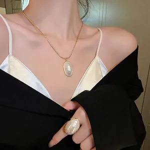 Parure collier et bague en perles ovales plaquées or portée par un mannequin femme