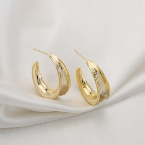 Minimalist 14K gold-plated C-shaped geometric hoop earrings on smooth white silk fabric