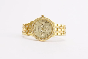 Close-up of golden Geneva watch with rhinestone bezel and polished metal link bracelet