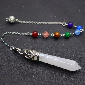 Macro detail of white crystal hexagonal pendulum with colorful chakra beads on silver chain