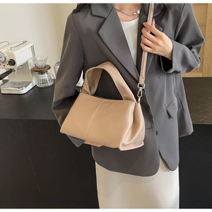 Chic beige textured leather bag with adjustable strap styled in a modern minimalist setting