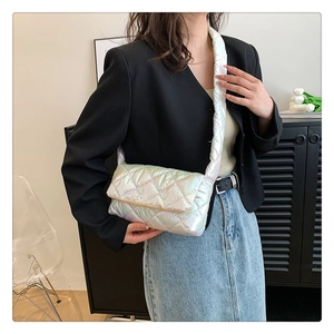 Detailed view of a white iridescent quilted puffer bag worn by a model in casual style