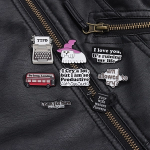 Détail des pin's émaillés Taylor Swift TTPD et badges de paroles sur une veste en cuir noir
