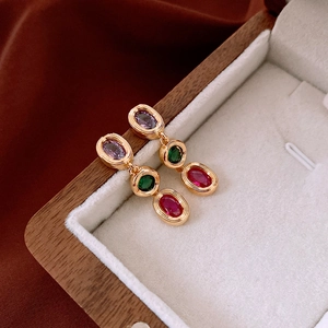 Macro detail of vintage gold earrings with purple, green and red oval gemstones