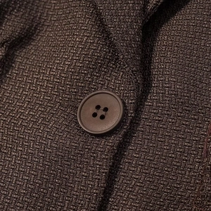 Close-up of dark brown woven tweed fabric texture and matching four-hole round button