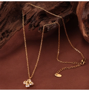 Detailed close-up of a gold clover pendant set with sparkling zircons on a wooden texture