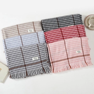 Thick houndstooth scarf with tassels and Luxe Cashmere label on a white background