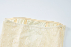 Dettaglio vita in pizzo beige con cerniera invisibile e fodera a pois neri