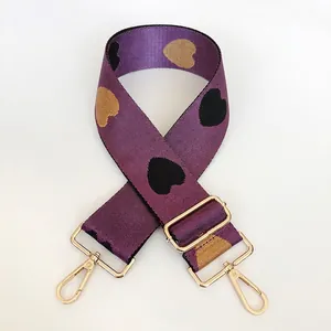 Detail of purple nylon bag strap with heart jacquard pattern and gold metal hook