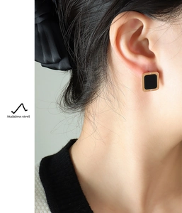 Detail of square titanium earrings with black inlay and engraved Roman numerals