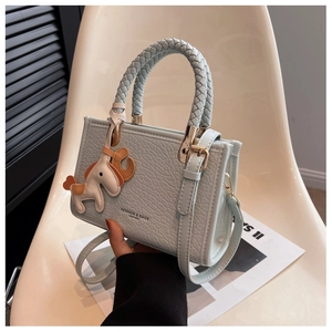 Close-up of light blue leather bucket bag with woven handle and horse charm detail
