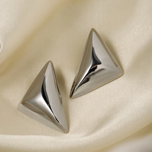 Orecchini a triangolo in argento lucido presentati su un elegante tessuto di seta beige