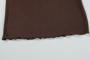 Detail of dark brown sheer mesh fabric featuring a ruffled lettuce edge and fine stitching
