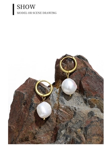 Baroque pearl earrings hanging on a natural stone prop with white background
