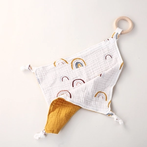 Detail of baby organic cotton rainbow muslin comforter with natural wooden teething ring