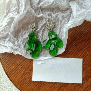 Macro view of French luxury teardrop emerald crystal earrings with rhinestone flower stud