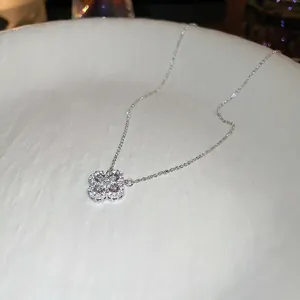 Elegant silver four-leaf clover pendant necklace with sparkling cubic zirconia on white surface