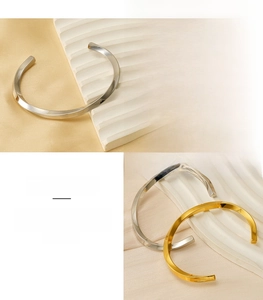 Gros plan de bracelets joncs torsadés en acier inoxydable doré et argenté sur texture