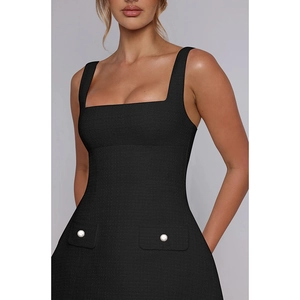 Close-up of black tweed sleeveless dress featuring square neck and pearl button pockets