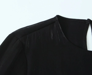 Detailed macro view of the round neckline and smooth satin fabric on a black shirt