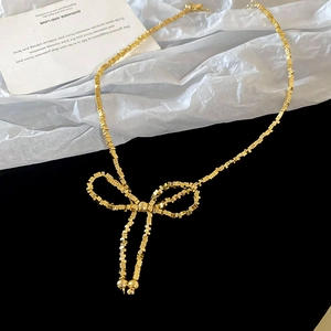 Vue détaillée d'un collier nœud papillon doré avec perles carrées sur fond de contraste