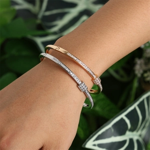 Détail macro de joncs en or rose et argent avec nœud pavé de zircons sur le poignet