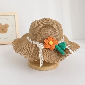 Detail of kids straw sun hat featuring orange flower, lace ribbon, and scalloped edges