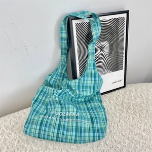 Close-up of a blue and green plaid canvas tote bag with white star logo and embroidery