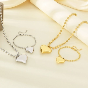 Detailed view of gold and silver heart pendant necklace and beaded bracelet jewelry set