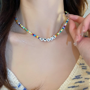 Detail of colorful beaded necklace with irregular pearls and Smile letter charms