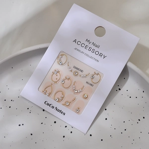 Detail view of water drop nail jewelry with gold lines, pearls, and rhinestones