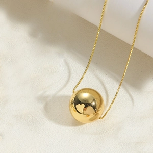 Polished 14K gold-plated spherical pendant on a delicate chain over minimalist background