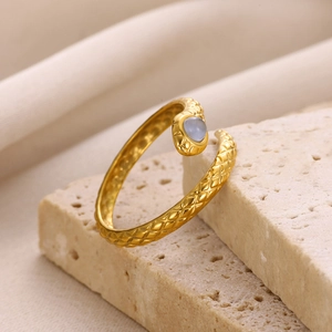 Macro detail of gold snake-textured ring featuring a round translucent blue gemstone