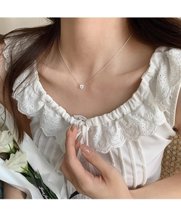 Detail of silver zircon pendant necklace on woman's neck with lace clothing