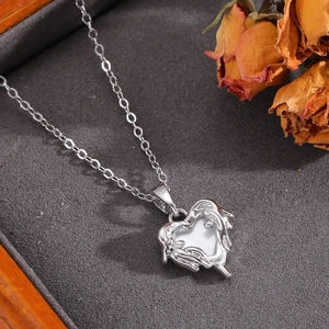 Dettaglio del ciondolo a cuore in argento su velluto grigio con rosa essiccata