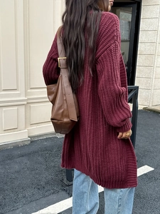 Vista street style di un lungo cardigan a maglia bordeaux con borsa a tracolla in pelle