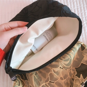 Detail of floral embossed cosmetic bag showing spacious interior and black jacquard fabric