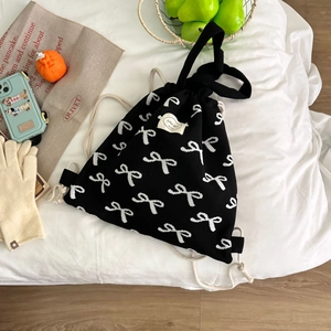 Detail eines schwarzen Strickrucksacks mit weißem Schleifenmuster und Lady Bug Etikett