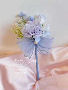 Detail of floral pen with silk bow, butterfly charm and pearls on pink satin background