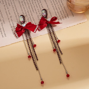 Elegant red bow tassel earrings with sparkling rhinestones and glass beads on vintage book