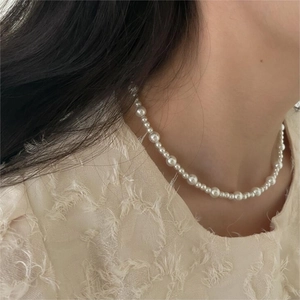 Close-up of elegant gradient pearl necklace on neck showing minimalist jewelry style