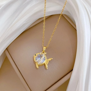Detailed close-up of a gold fish pendant necklace with sparkling cubic zirconia inlay