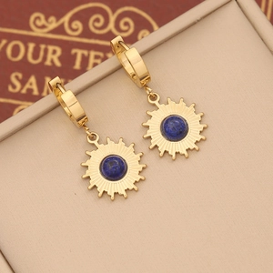Detailed close-up of sunburst gold earrings featuring center blue stone inlay and hoop design