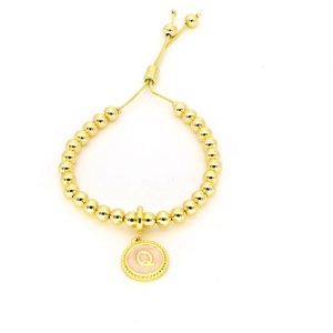 Gros plan détaillé du bracelet en perles dorées 18k avec pendentif lettre Q rose