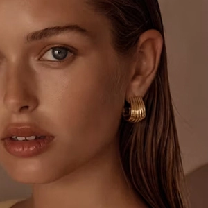 Close-up of a model wearing gold double-layer spiral textured stud earrings in metal